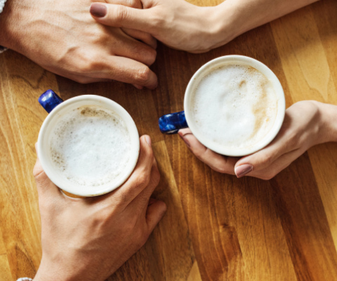 Two sets of hands holding coffee cups